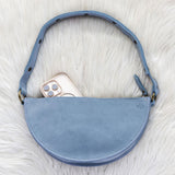 Blue suede handbag with a phone inside on a white fur surface