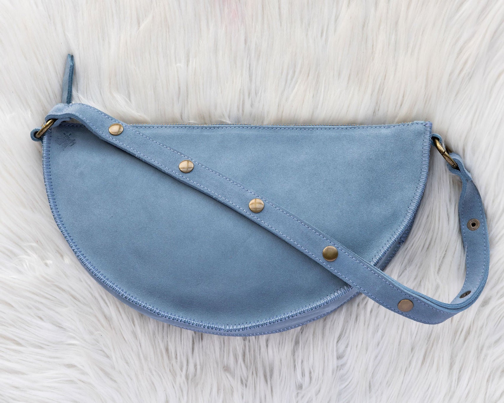 Blue leather bag with gold studs on a white fur background