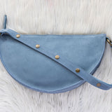 Blue leather bag with gold studs on a white fur background
