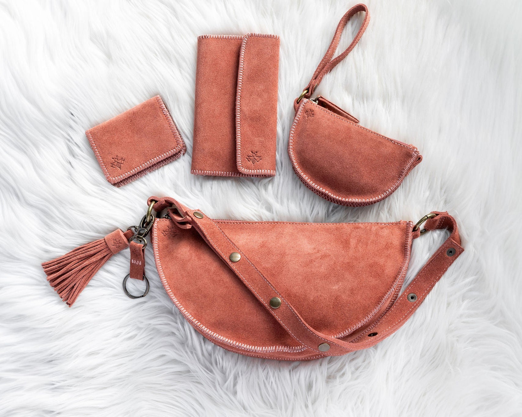 Set of mauve leather bags and wallets on a textured white surface