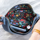 Floral-patterned pouch with a blue zipper held by hands on a white background