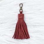 Red tassel keychain on a textured white background