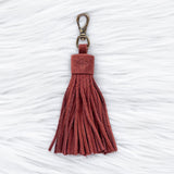 Red tassel keychain on a textured white background