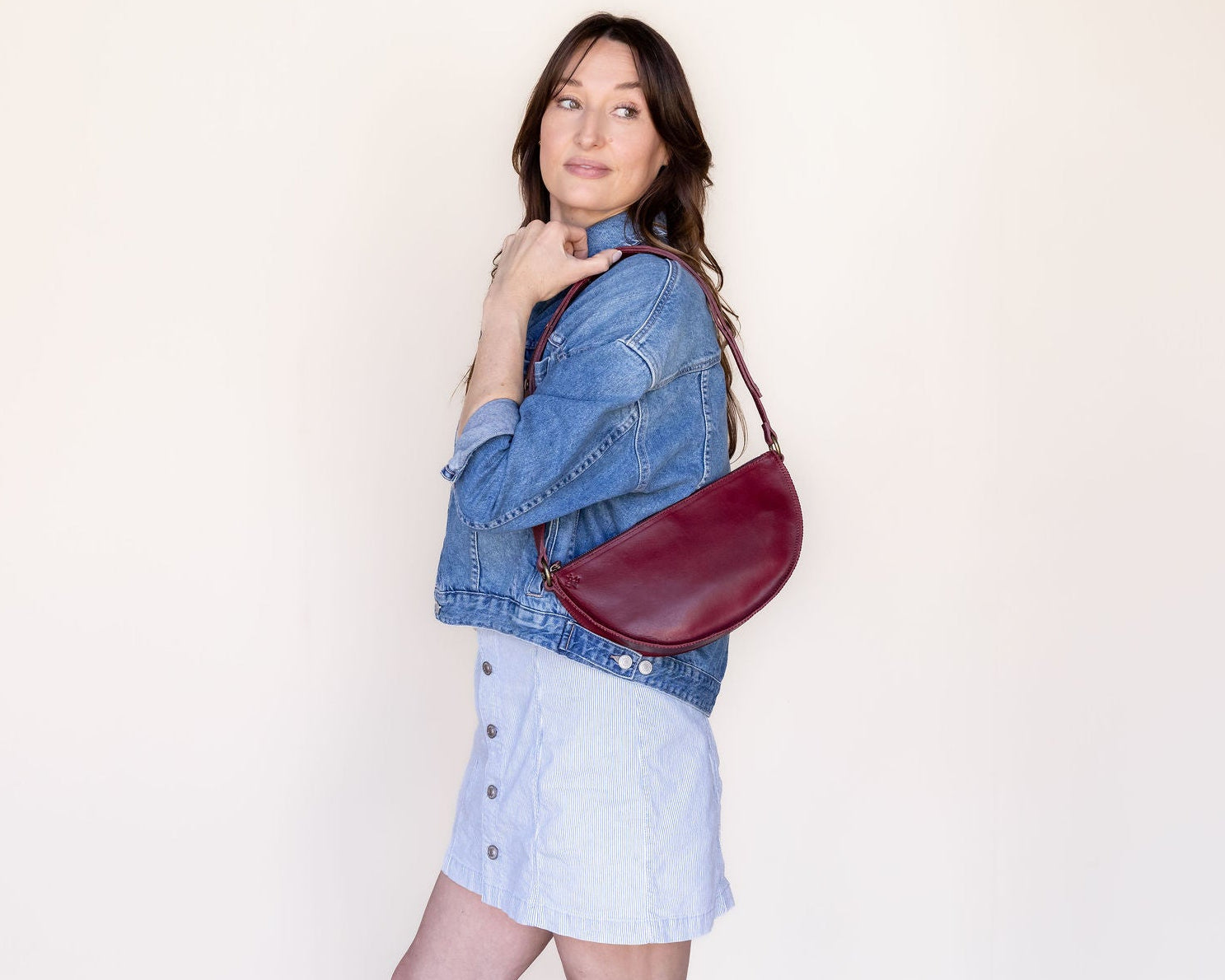 Woman holding a red handbag against a plain background