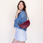 Woman holding a red handbag against a plain background