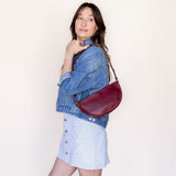 Woman holding a red handbag against a plain background