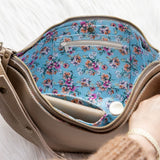 Handbag with floral interior lining held by a person on a white background