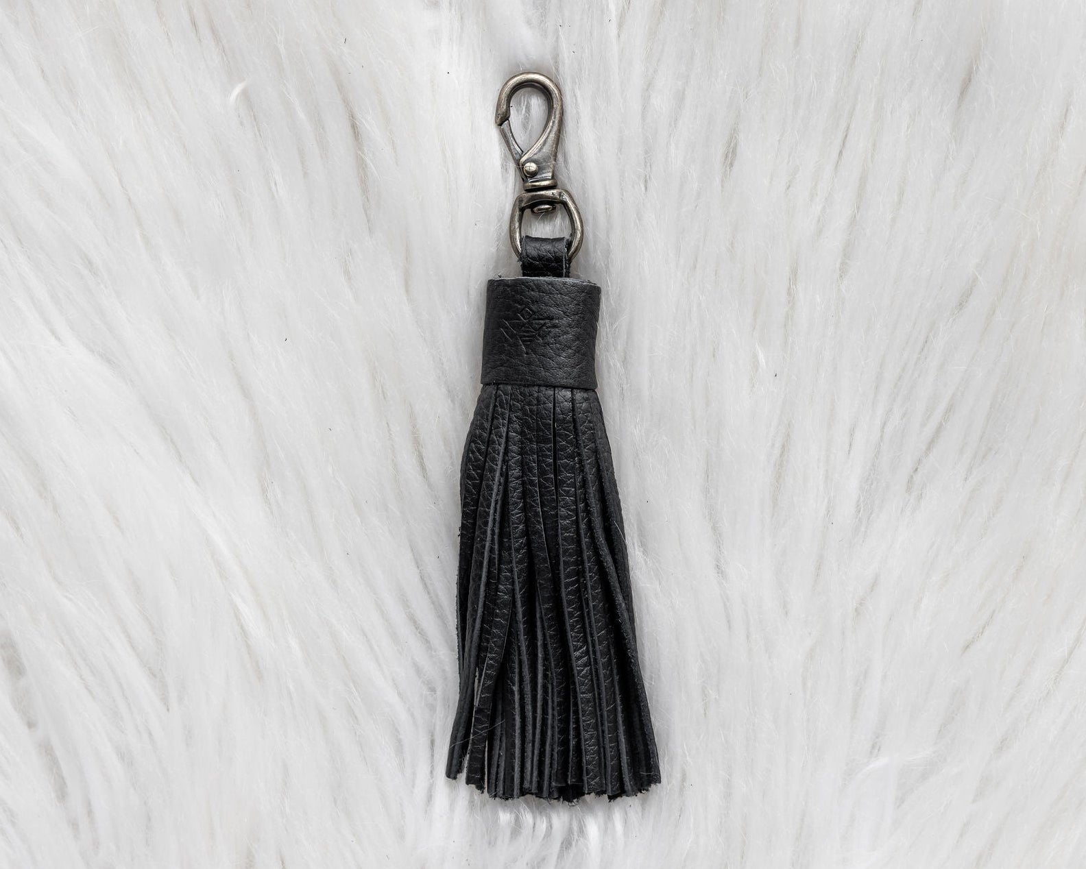 Black tassel keychain on a white fur background