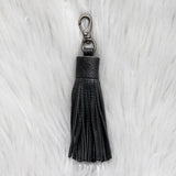 Black tassel keychain on a white fur background
