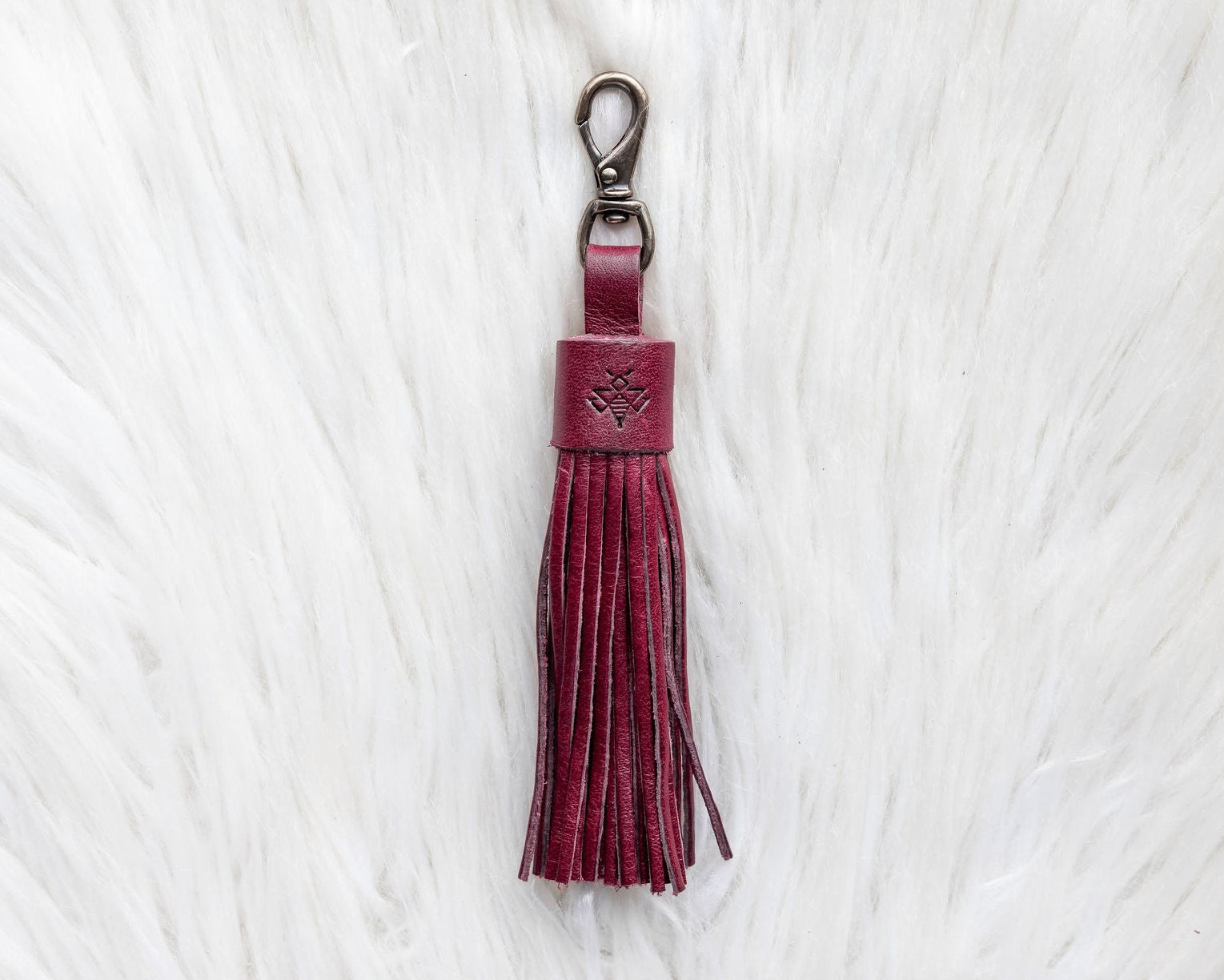 Maroon tassel keychain on a white textured background