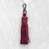 Maroon tassel keychain on a white textured background