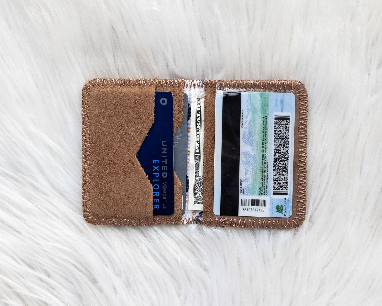 Brown cardholder with cards and money on a white textured surface