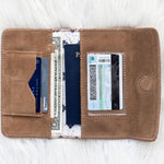 Brown leather wallet with cards and a passport on a white surface