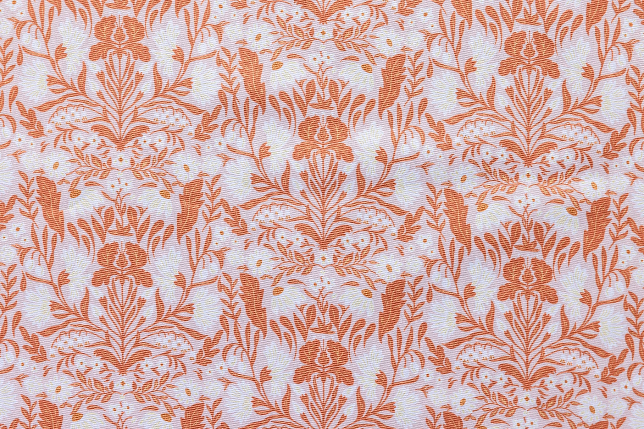 Patterned fabric with orange floral design on a light background