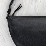 Close-up of a black leather pouch with a zipper on a white textured background