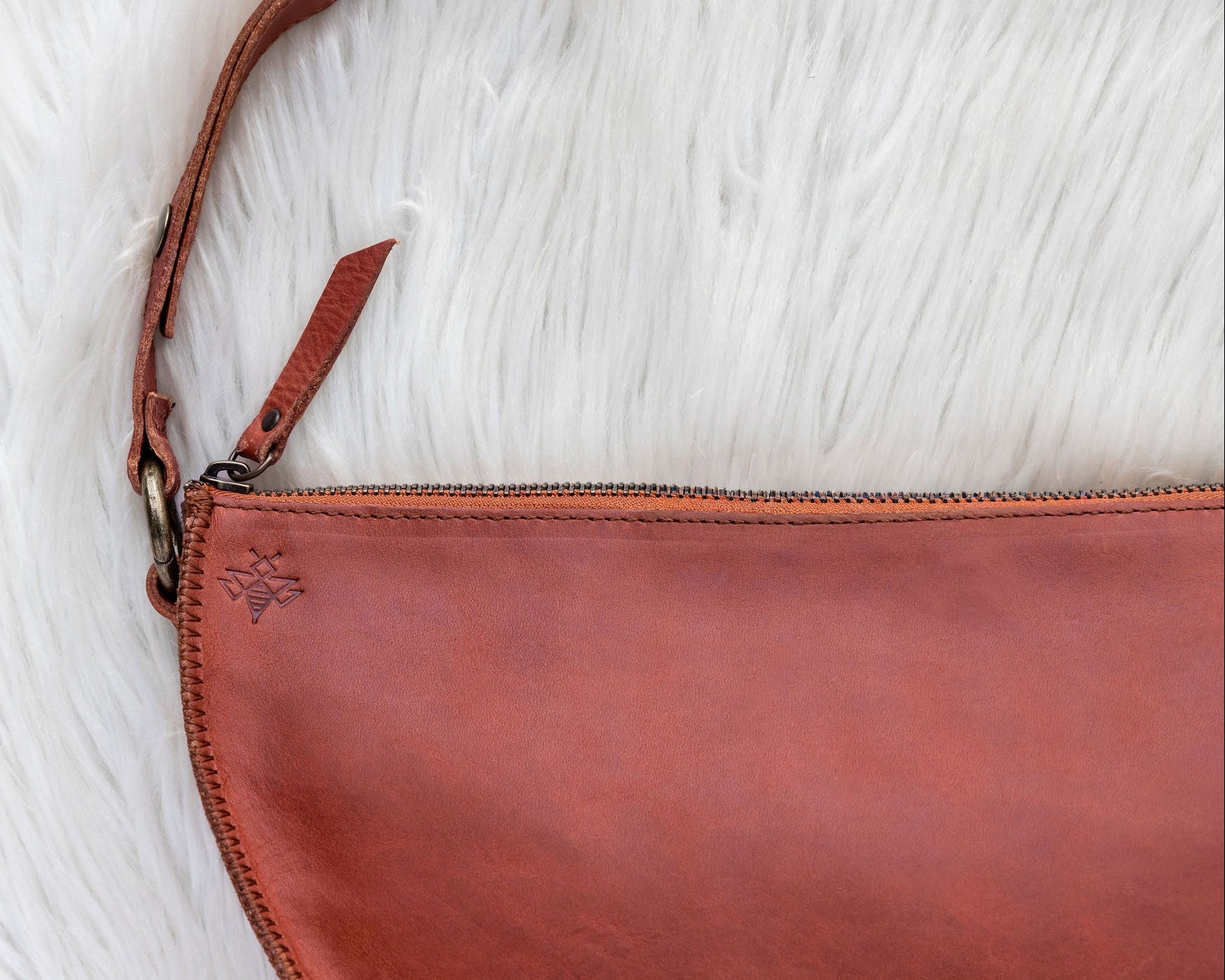 Brown leather clutch bag on a white textured surface