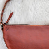 Brown leather clutch bag on a white textured surface