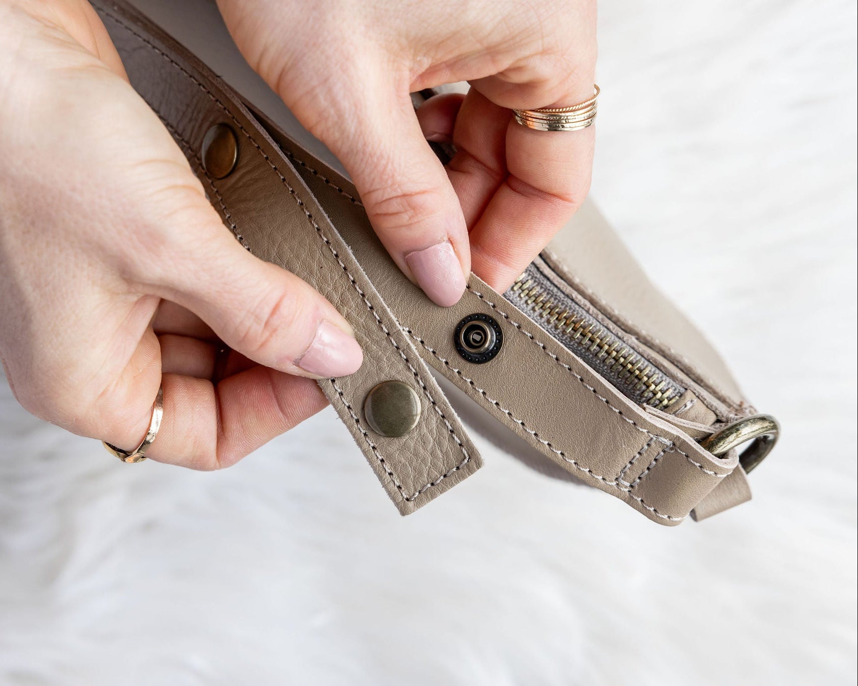 Close-up of hands holding a beige leather wallet on a light background