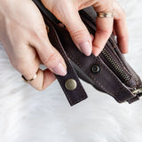 Close-up of hands holding a brown leather wallet on a white background