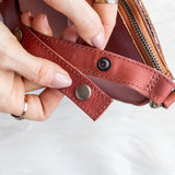Close-up of a hand holding an open red leather wallet with a white background