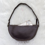 Brown leather bag with a phone inside on a white textured surface