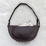 Brown leather bag with a phone inside on a white textured surface