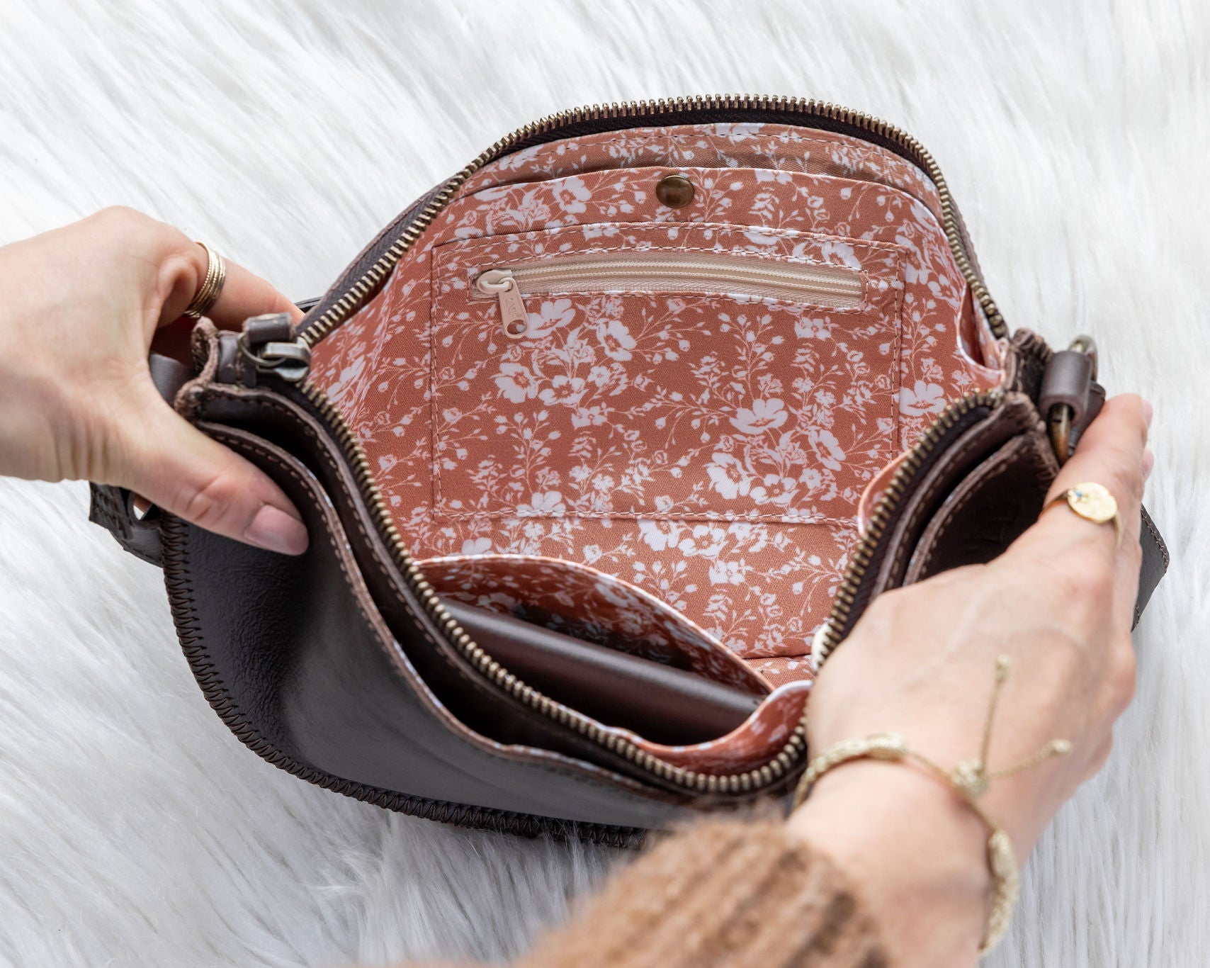 Person opening a patterned handbag on a white background