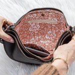 Person opening a patterned handbag on a white background