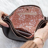 Person opening a patterned handbag on a white background