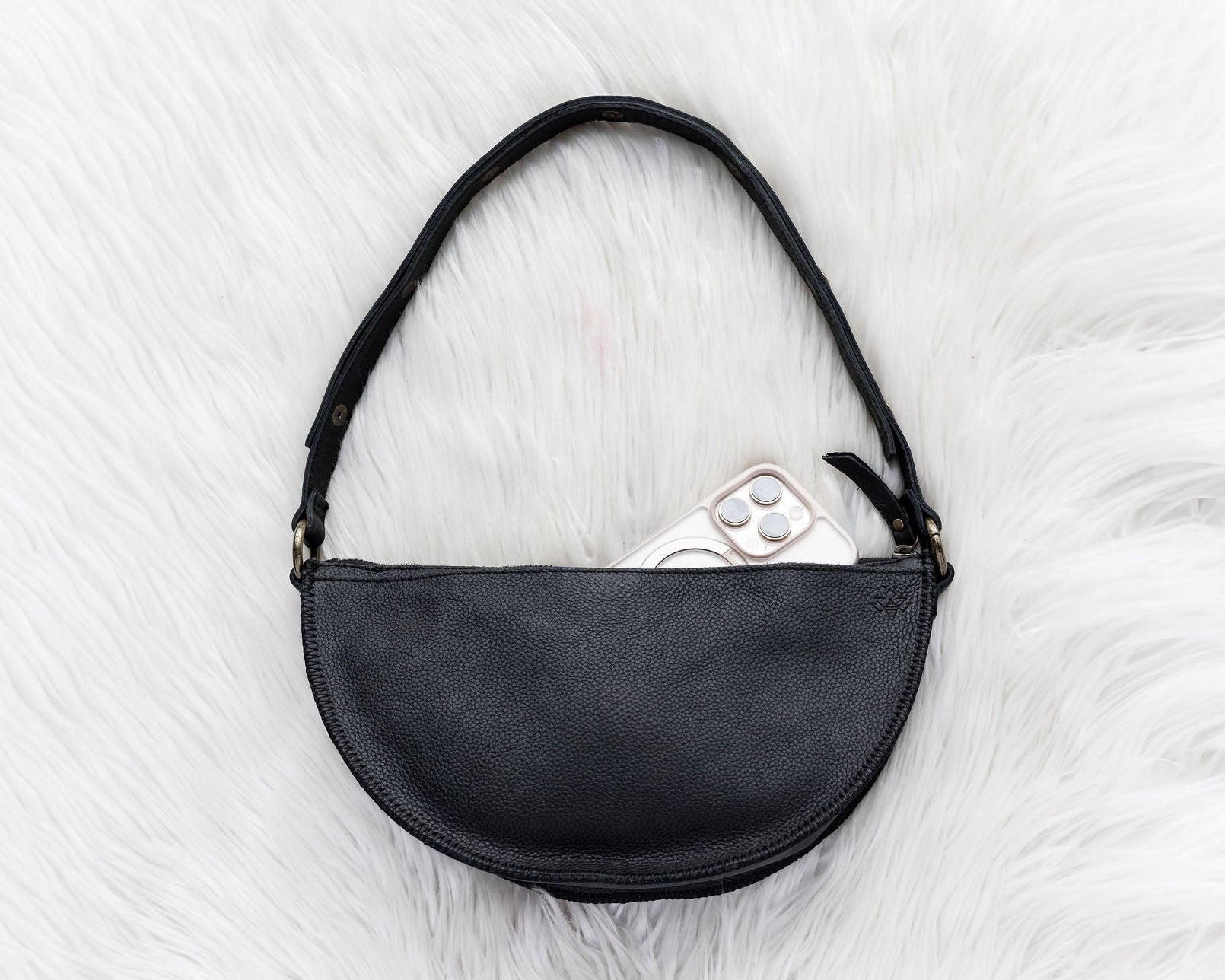 Black leather bag on a white fur surface