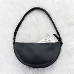 Black leather bag on a white fur surface