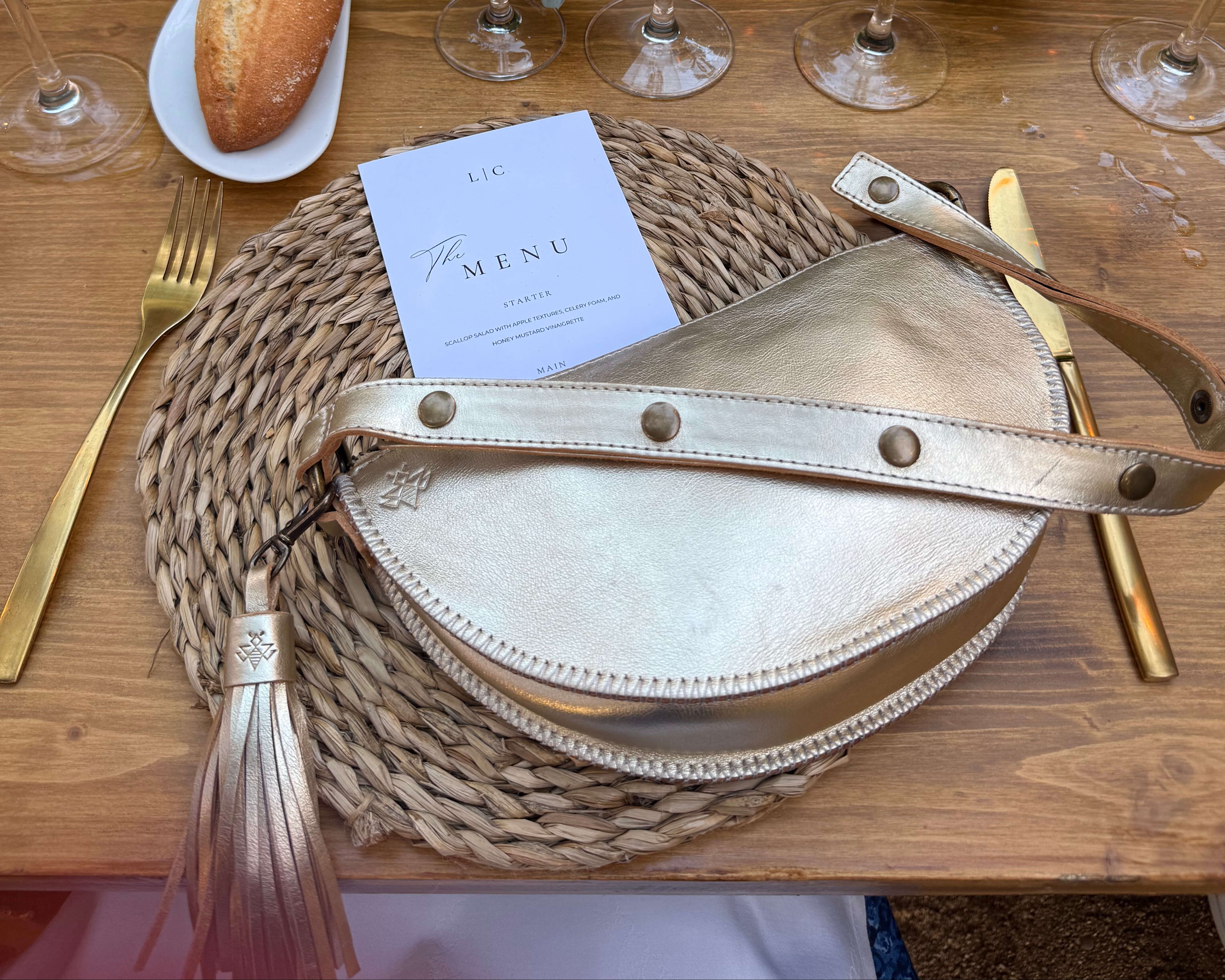 Table setting with wine glasses, bread, and decorative elements on a wooden table.