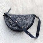 Semicircular handbag with floral pattern on a white fluffy surface
