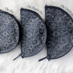 Three floral-patterned pouches labeled 'The Bee', 'The Biggie Bee', and 'The Queen Bee' on a white fluffy surface.