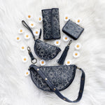 Set of Navy  handbags with floral embroidery on a white surface with daisies.
