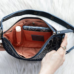 Open navy handbag with a brown interior on a white fluffy surface
