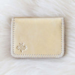 Beige cardholder with a brand logo on a white fur background