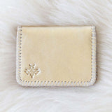 Beige cardholder with a brand logo on a white fur background