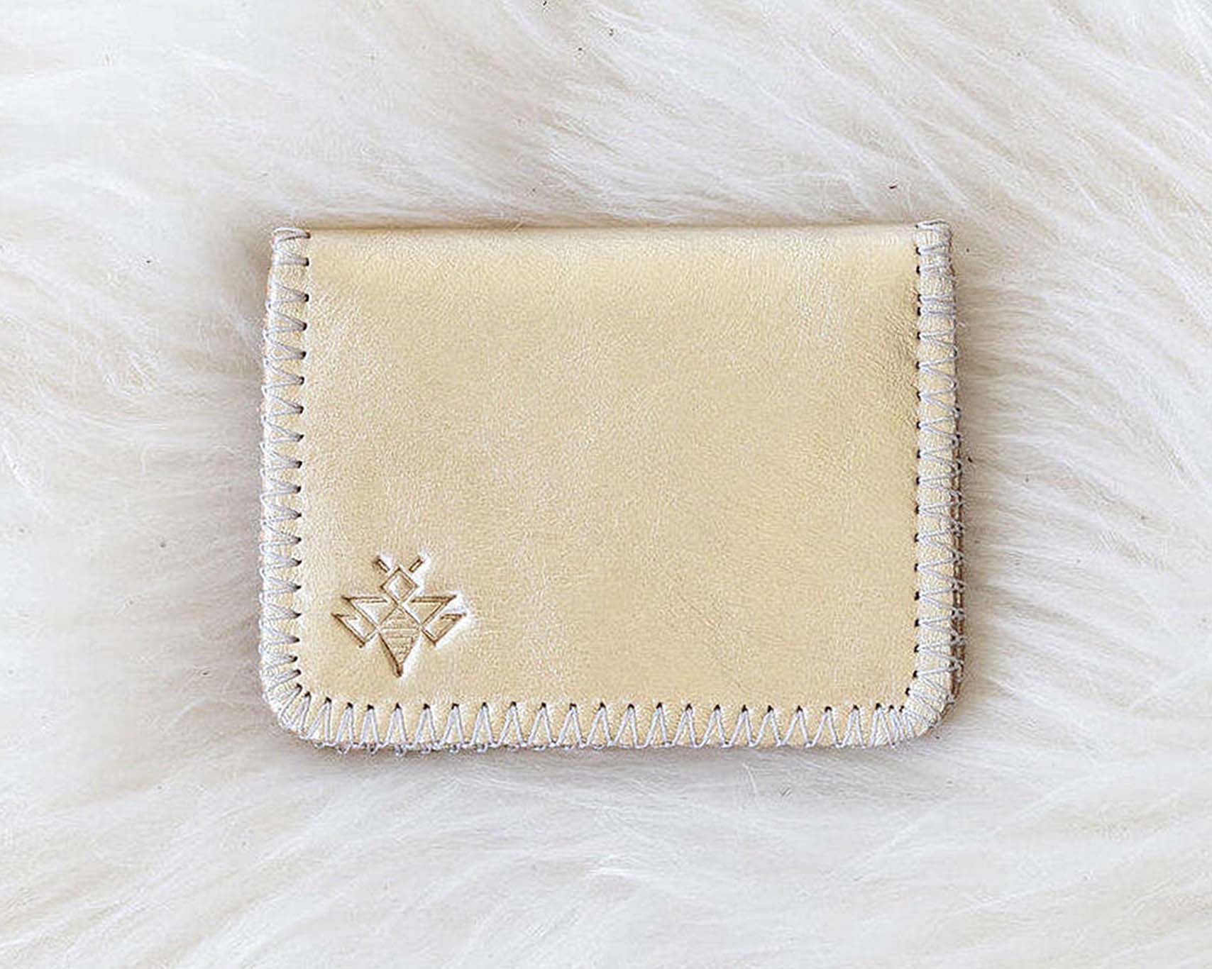 Beige cardholder with a brand logo on a white fur background