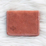 Pink suede wallet on a white textured surface