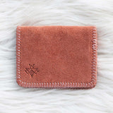 Pink suede wallet on a white textured surface