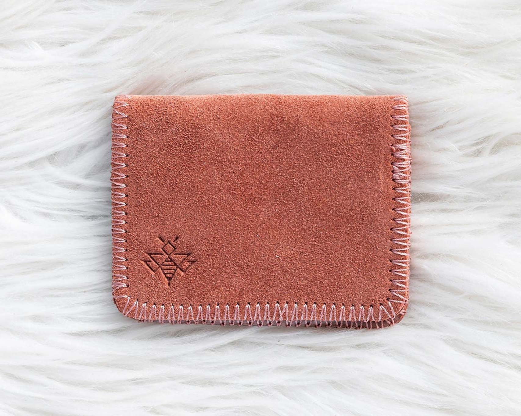 Pink suede wallet on a white textured surface