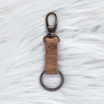 Keychain with brown leather strap on a textured white surface