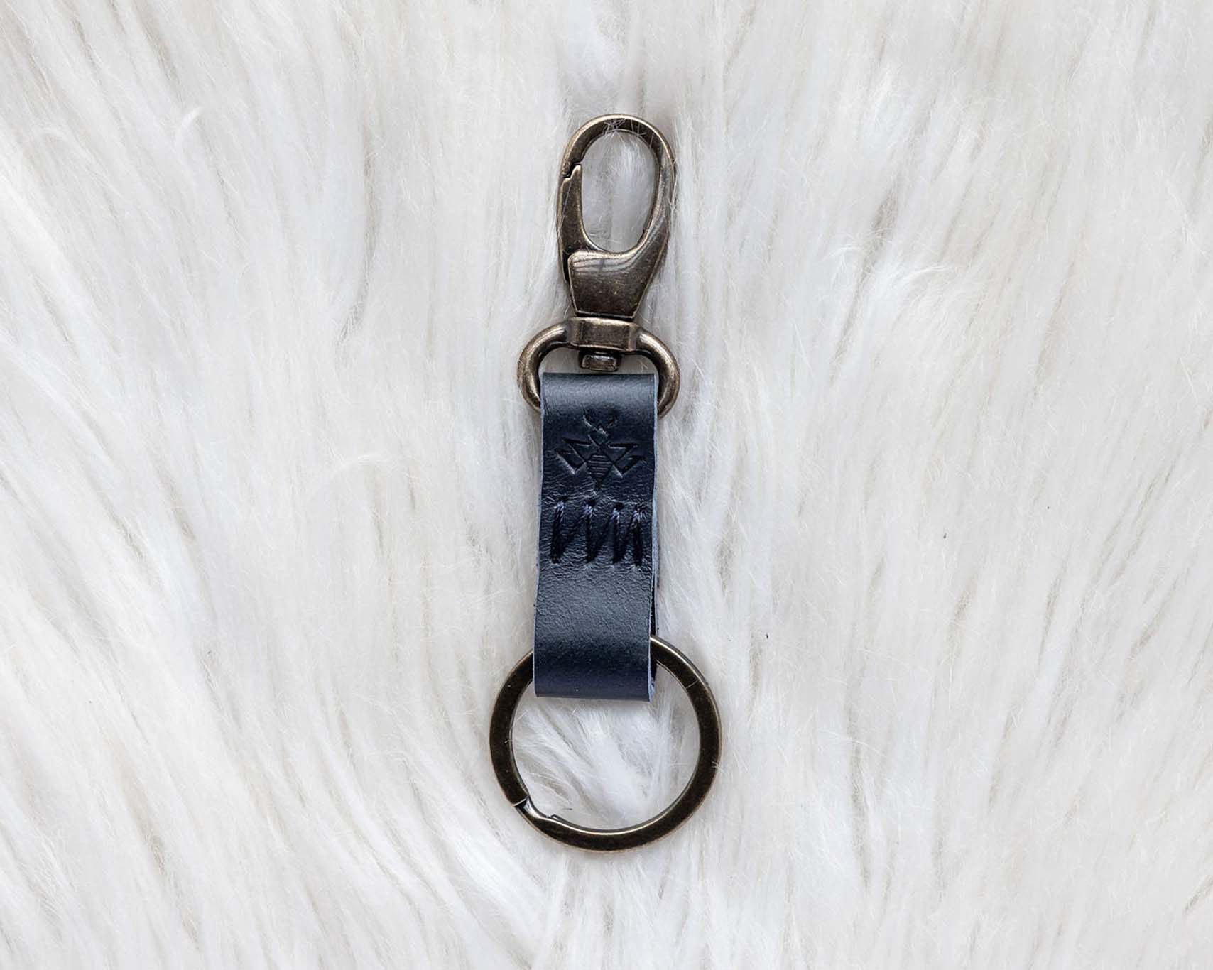 Black leather keychain with metal clip on a white textured background