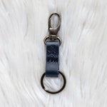 Black leather keychain with metal clip on a white textured background