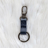 Black leather keychain with metal clip on a white textured background