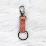 Keychain with pink leather strap on a textured white surface