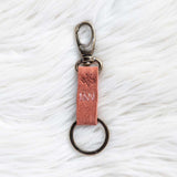 Keychain with pink leather strap on a textured white surface