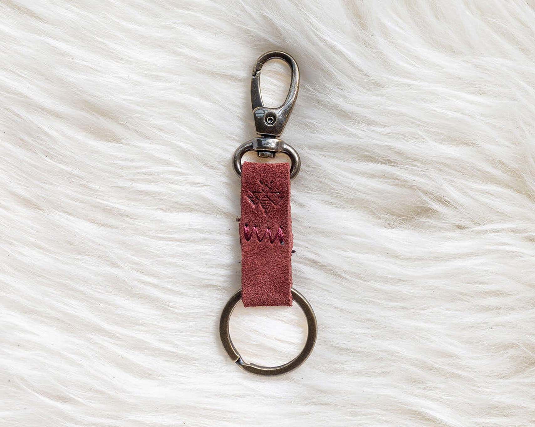 Red leather keychain with metal clasp on a white fur surface