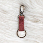 Red leather keychain with metal clasp on a white fur surface